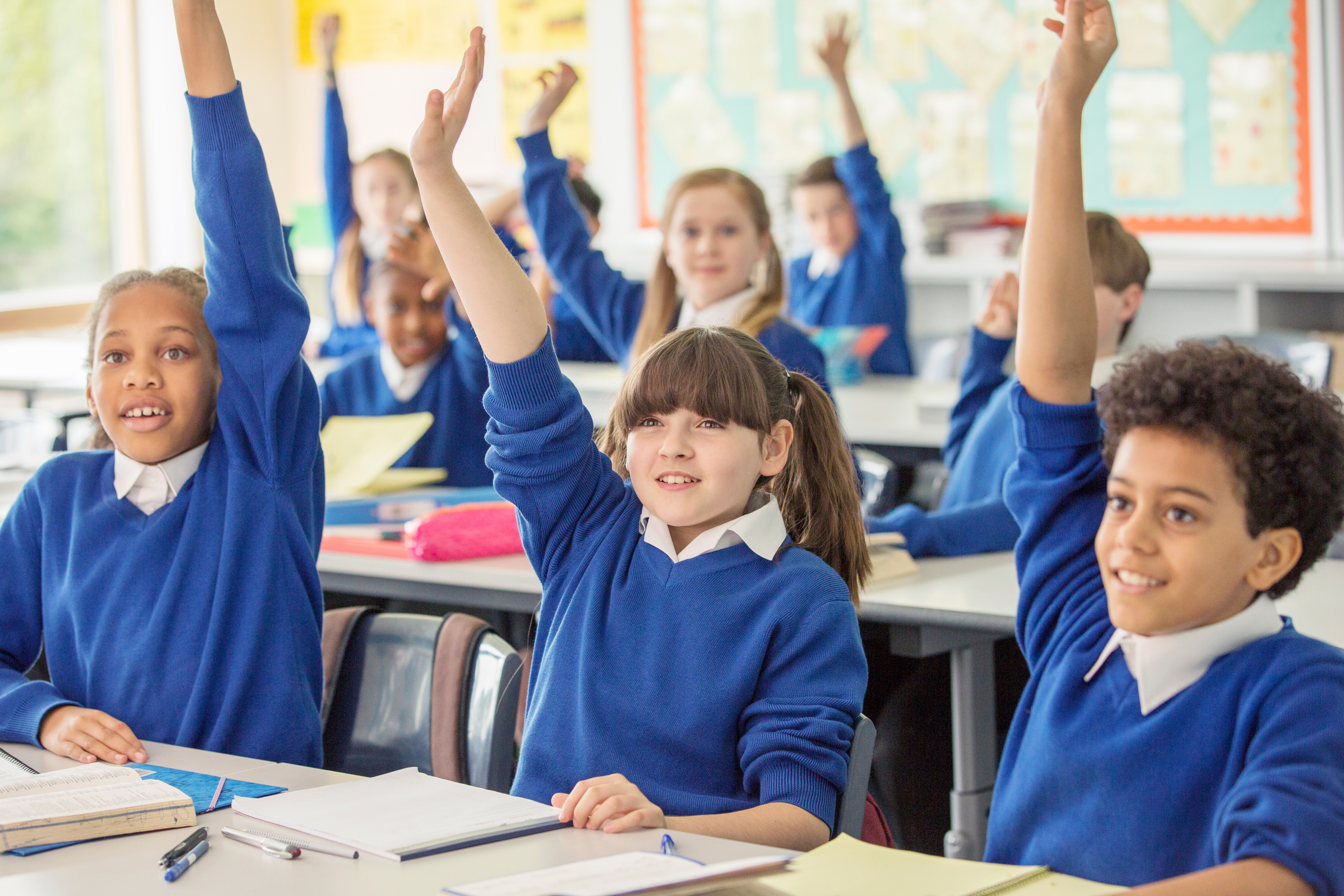 Kids with hands raised in classroom