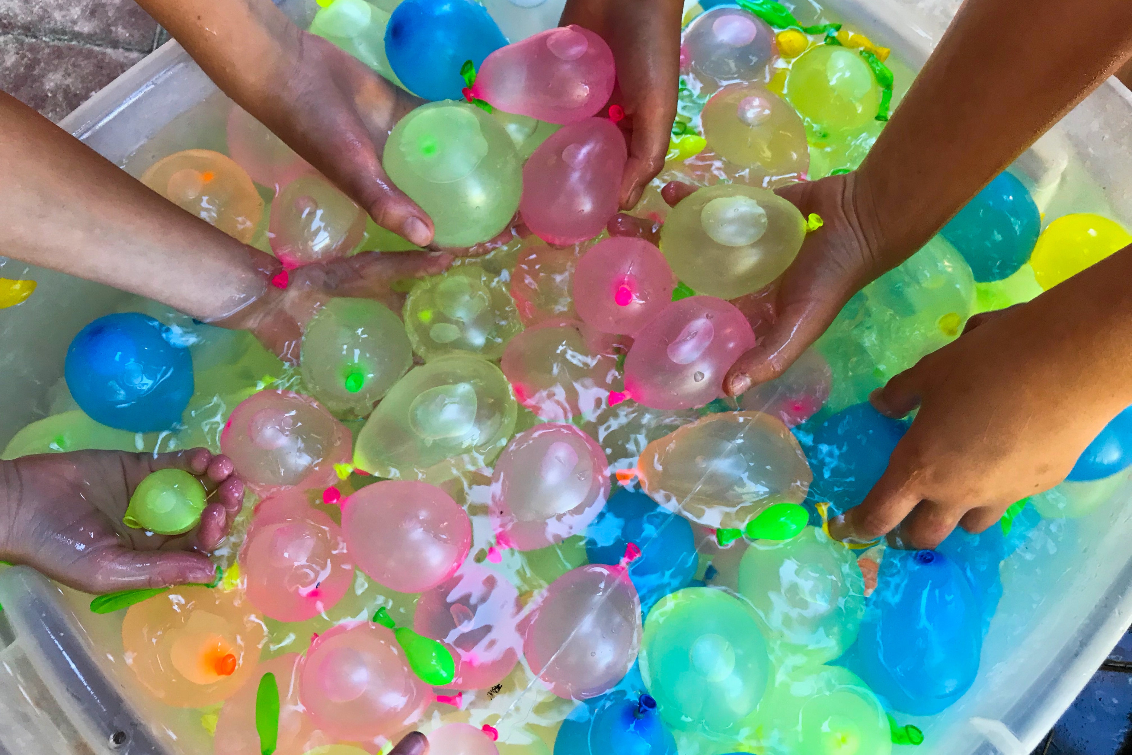 Kids hands grabbing water balloons