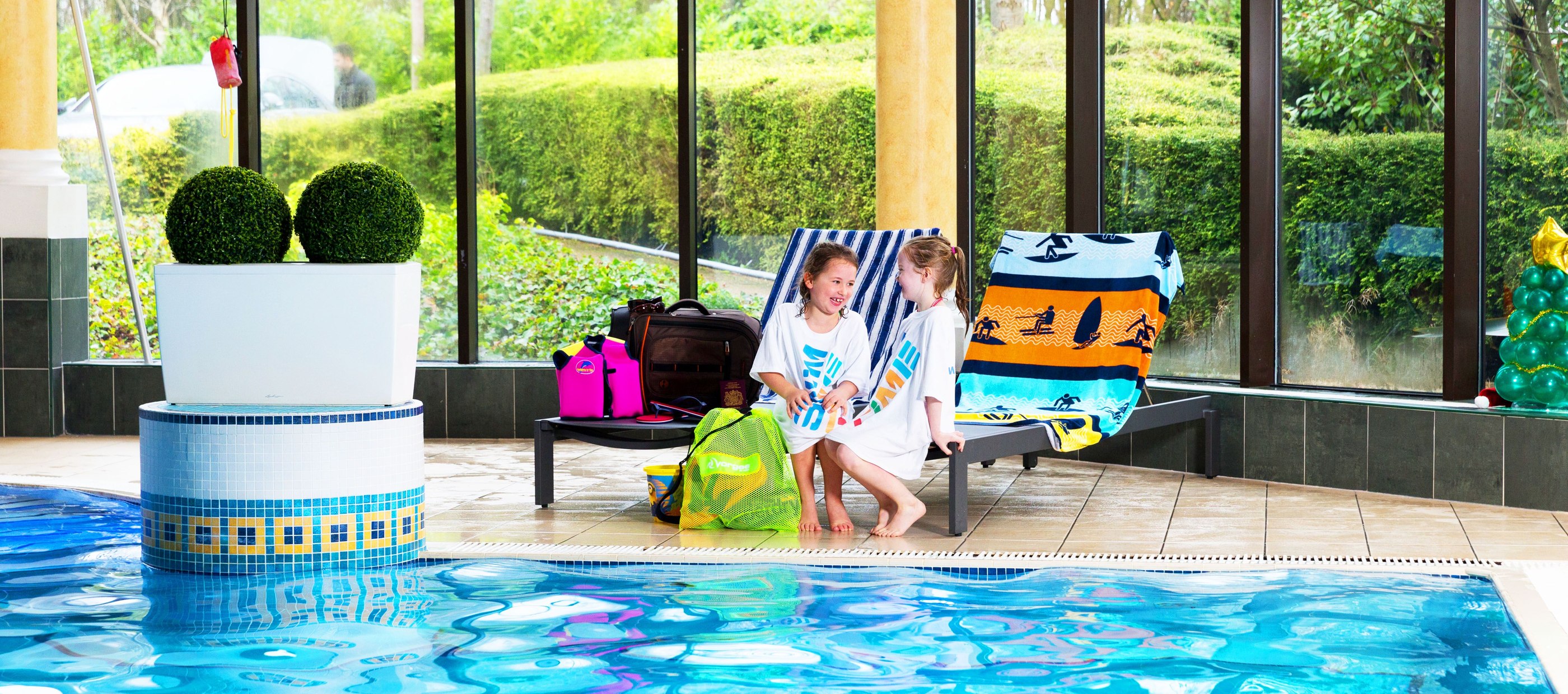 Children resting by side of swimming pool