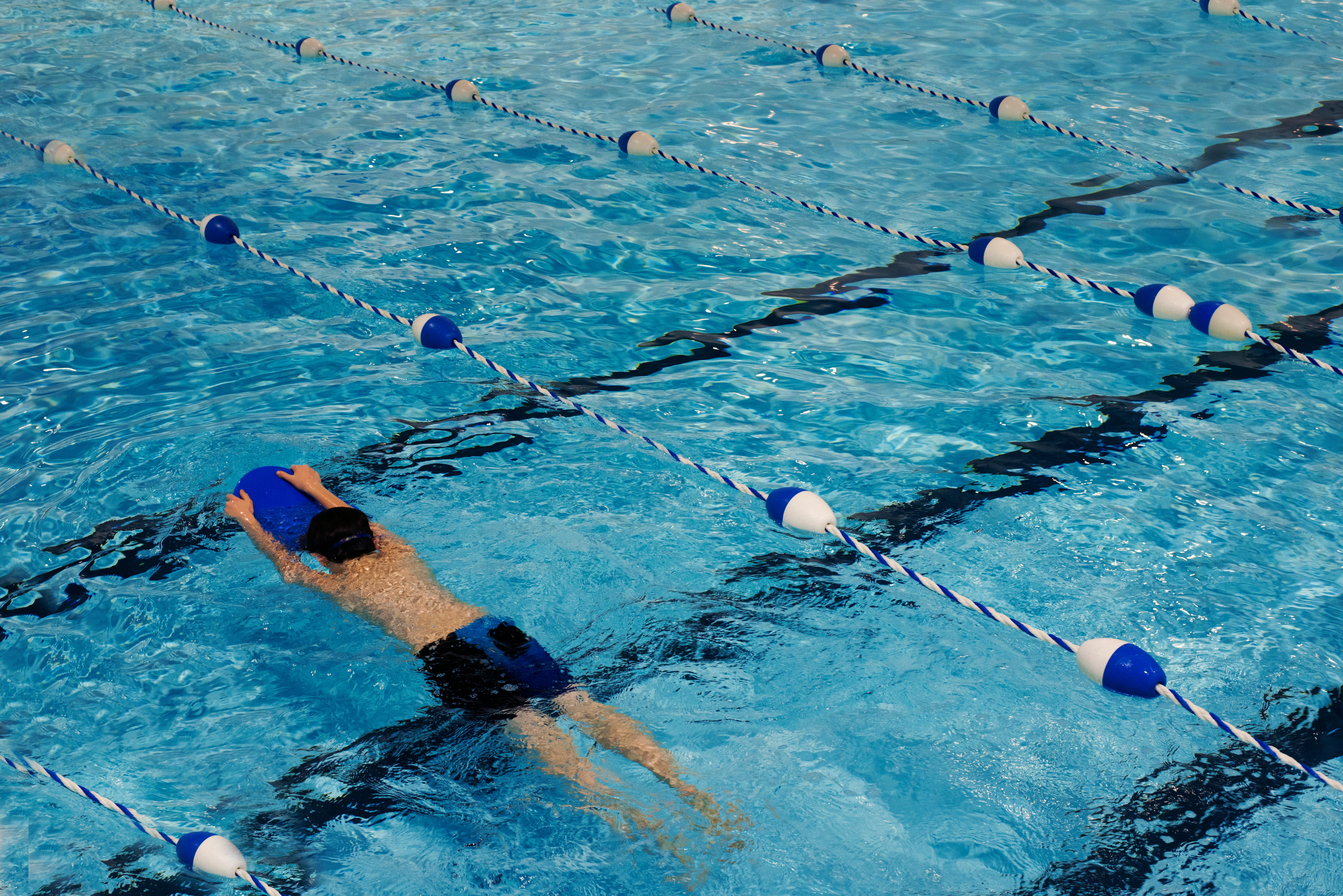 Child swimming in pool with kickboard